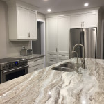 Kitchen with white cabinets and center island with sink and marble countertop
