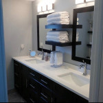 bathroom with dual vanity and center towel shelves
