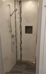 bathroom shower with large marble tiles and adjustable-height shower head