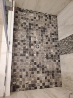 raised bathroom shower with floor tiles and center drain