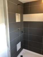 bathroom shower with large dark tiles and insets