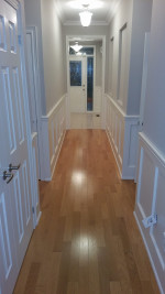 two-tone gray and while paneled hallway with wood flooring