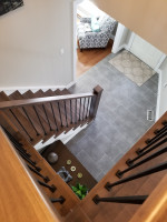 medium-dark wood stairway, looking down on tiled entrway