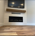 in-wall fireplace with white paneling and wood mantle and TV