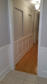 two-tone gray and while paneled hallway with wood flooring