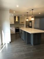 kitchen with white cabinets, dark wood flooring, center island with sink, and twin pendant lights