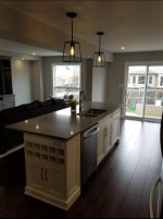 kitchen with dark wood flooring, center island with sink, and twin pendant lights