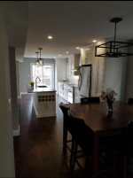 kitchen center island with sink, wood flooring, pot lights and pendant lighting