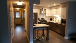 entryway and hall leading to kitchen with breakfast table, wood flooring, and pot lights