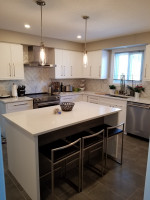 kitchen island with seating for three, pendant lights, white cabinets, tiled back-splash