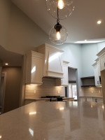 pendant lights above kitchen island with vaulted ceiling and paneled vent hood