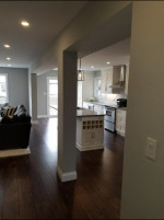 kitchen with dark wood flooring, pot lights, and pillar adjacent to family room