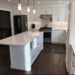 kitchen with white granite center island, tiled back-splash, and dark appliances